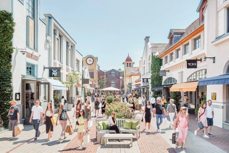 Gut besuchte Einkaufsstraße im Ingolstadt Village an einem Sommertag
