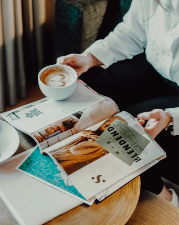 Frau ließt Zeitung und trinkt Cappuccino