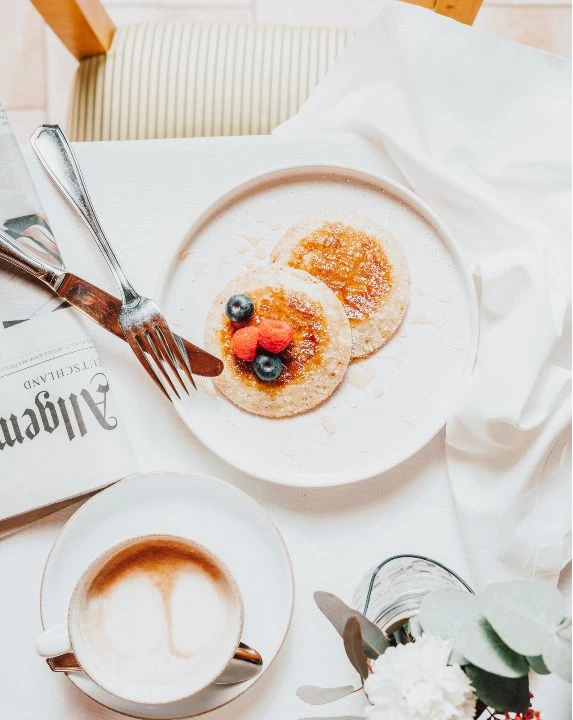Kulinarik 9 Pancakes und Cappuccino am Frühstücktstisch