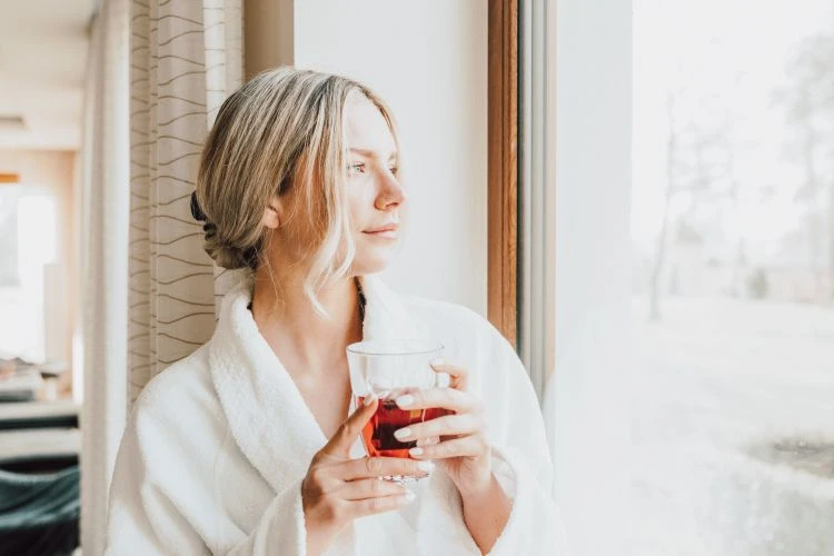Frau im Bademantel mit Blick nach Draußen