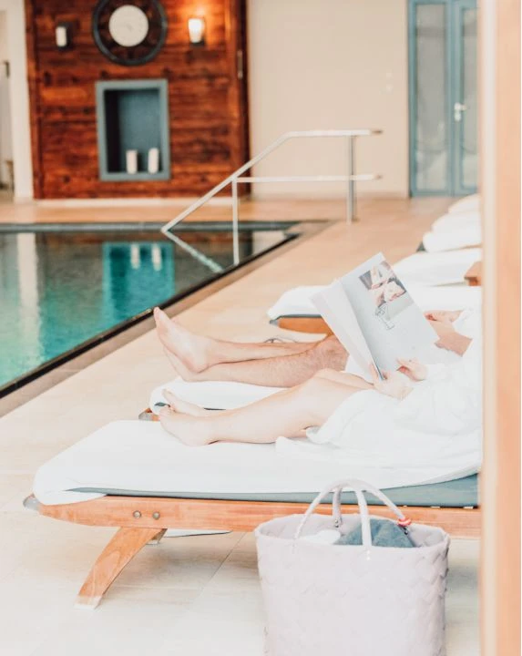 Babymoon 1 Paar auf Liegestühlen neben dem Pool mit Badekorb