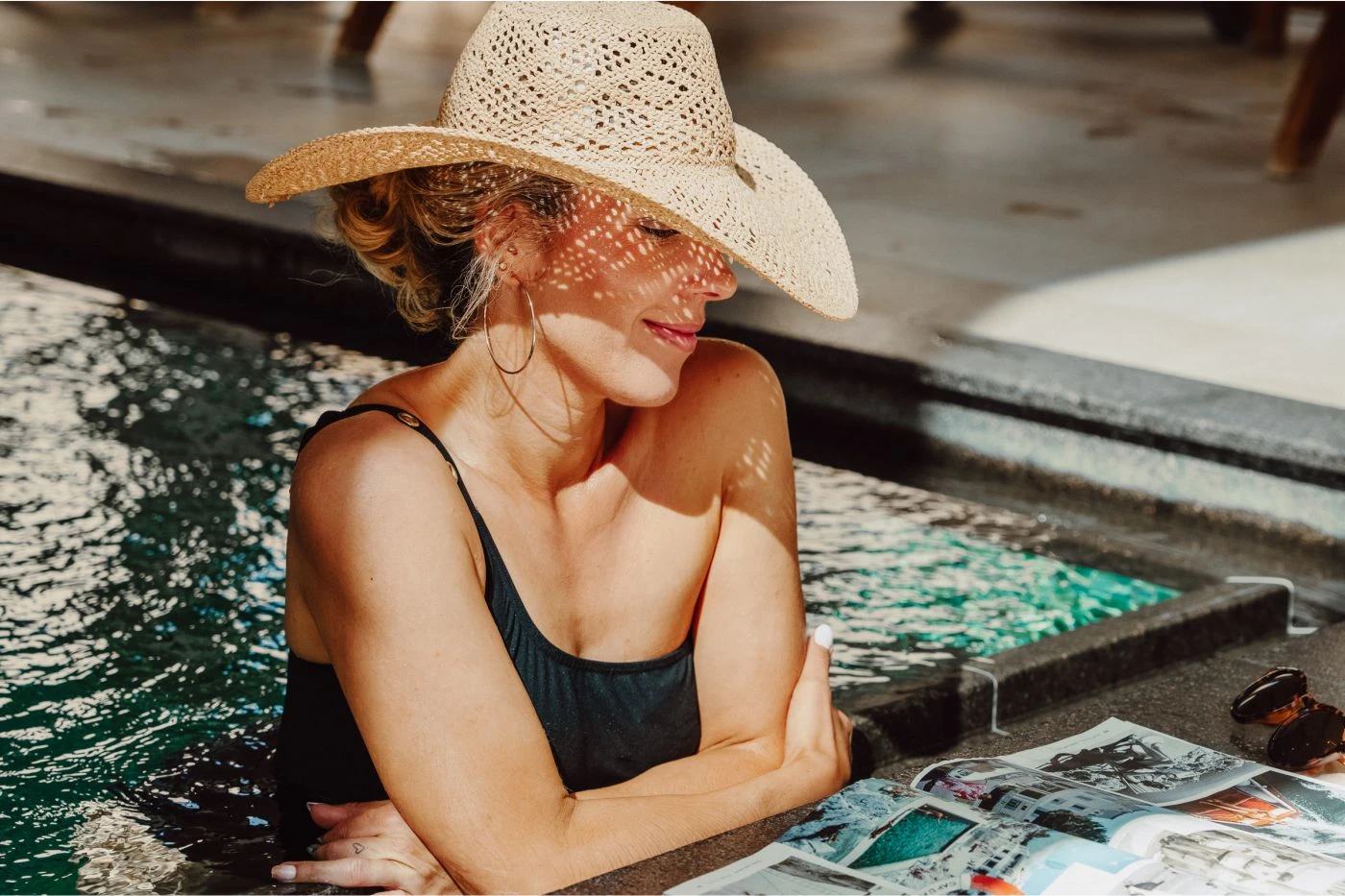 Frau mit Sommerhut am Poolrand