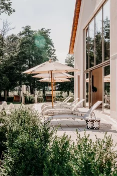 Dein Wellnesshotel: Luxus und Natur vereint 36 Liegestühle vor Badhaus in der Sommersonne