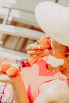 Frau isst Erdbeeren im Liegestuhl