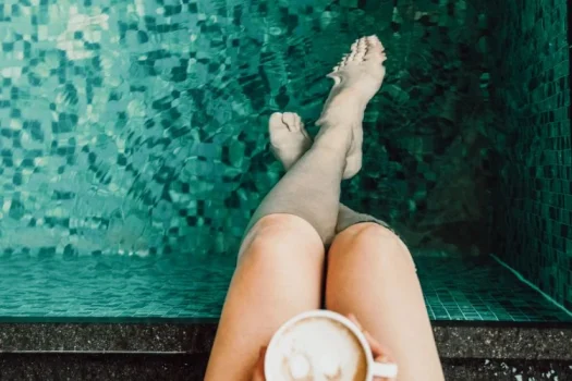 Frau am Poolrand mit Kaffee