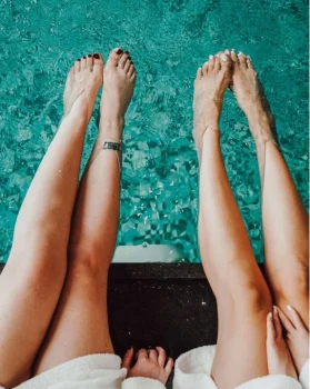 Zwei Freundinnen lassen Beine in den Pool hängen