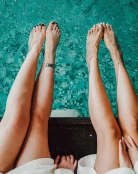 Zwei Freundinnen lassen Beine in den Pool hängen